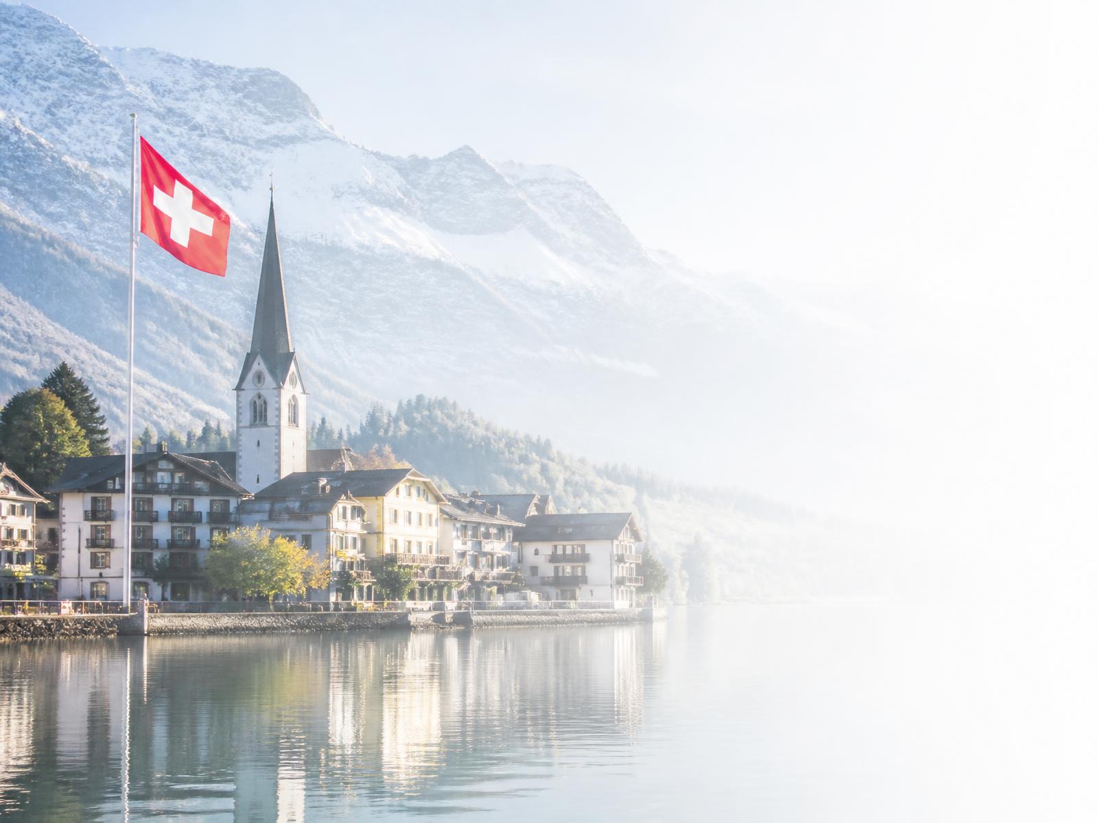 Swiss lakeside town with the Swiss flag and alpine mountains